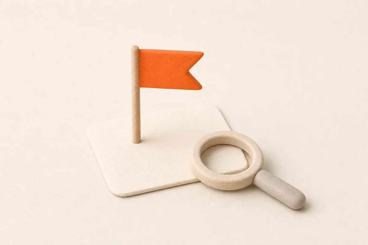 A small paper flag planted on a plain card, with a magnifying glass resting beside it.